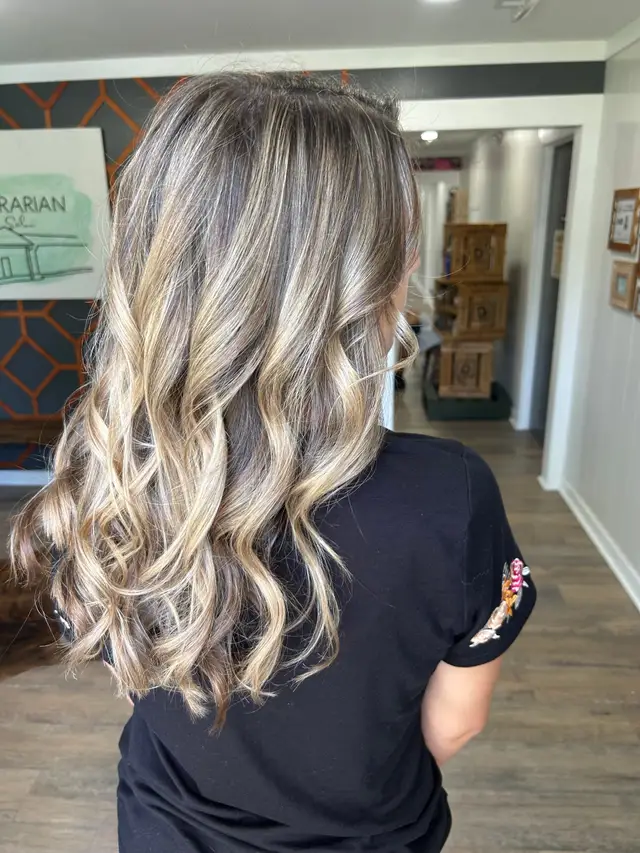 Voluminous curled balayage blonding with natural root shadow