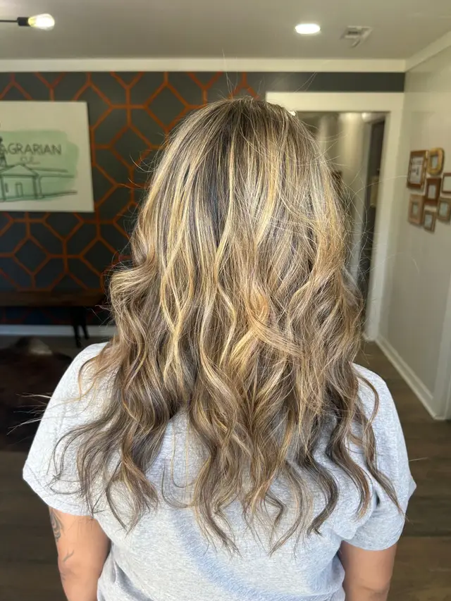 Warm balayage blonding with soft face-framing highlights on long wavy brunette hair